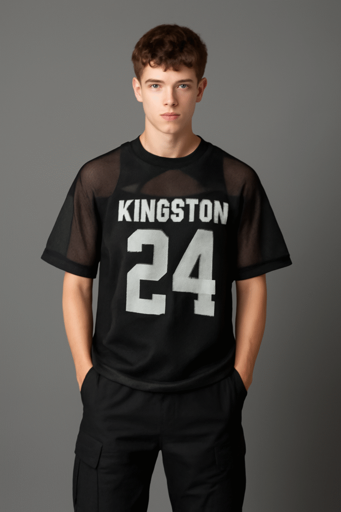 Young man wearing a mesh football jersey with bold "KINGSTON" print, styled with black cargo pants for a Y2K-inspired fashion look in 2025.